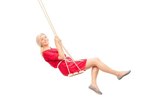 Joyful young woman swinging on a swing a smiling