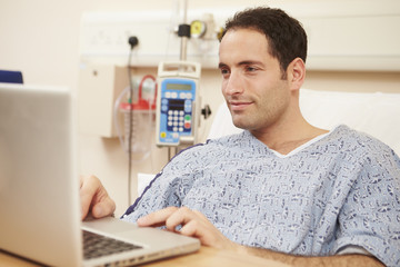Fototapeta na wymiar Male Patient Using Laptop In Hospital Bed