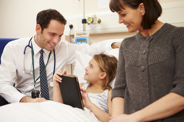 Doctor Talking To Mother And Daughter In Hospital Bed