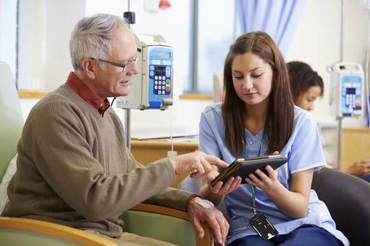 Man Having Chemotherapy With Nurse Using Digital Tablet