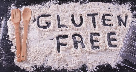 Word written in flour, along with a spoon and a wooden fork food and a grater