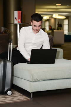 handsome young business man traveler working with laptop in hotel lobby