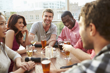 Group Of Friends Enjoying Drink At Outdoor Rooftop Bar