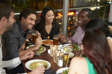 Group Of Friends Enjoying Evening Meal In Restaurant