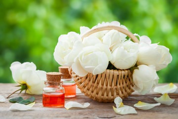 Wicker basket with roses bunch and bottles of essential oil.