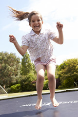 Portrait Of Girl Bouncing On Trampoline In Garden