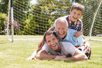 Grandfather, Grandson And Father With Football In Garden