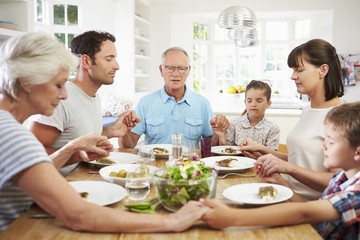 Obraz na płótnie Canvas Multi Generation Family Praying Before Meal At Home