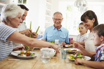 Multi Generation Family Eating Meal Around Kitchen Table