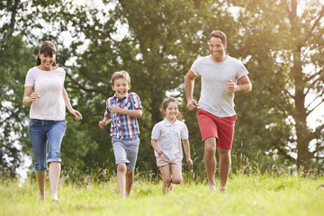 Smiling Family Running Across Summer Field Together