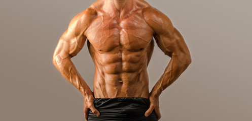 Obraz premium Strong bodybuilder with six pack.Strong bodybuilder man with perfect abs, shoulders,biceps, triceps and chest, personal fitness trainer flexing his muscles
