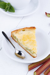 Tasty slice of rhubarb pie on white wooden table.