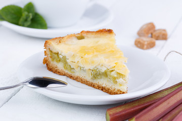 Tasty slice of rhubarb pie on white wooden table.
