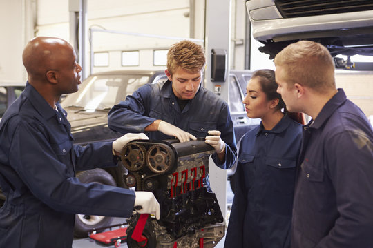 Teacher Helping Students Training To Be Car Mechanics