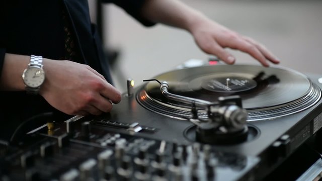 Young DJ spinning in a suit at a party on the terrace