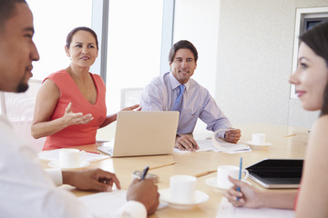 Fototapeta premium Four Hispanic Businesspeople Having Meeting In Boardroom