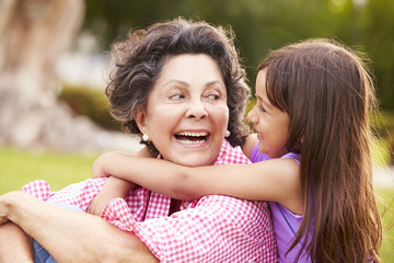 Grandmother And Granddaughter Sitting In Park Together