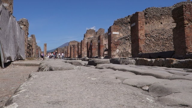 Group of tourists visiting the city of Pompeii, the entire town is an archaeological site from Roman times buried by the eruption of the volcano Vesuvius. 