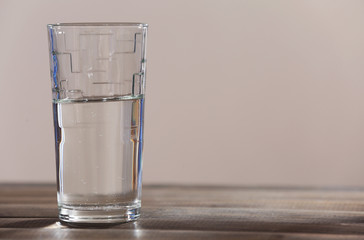 Glass of clean mineral water on wooden planks surface and light background