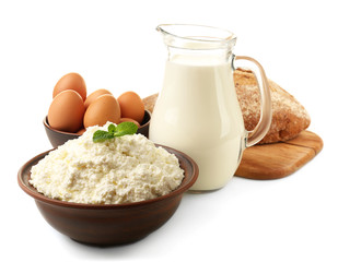 Dairy products in pottery, glass jug of milk, eggs and loaf of bread isolated on white