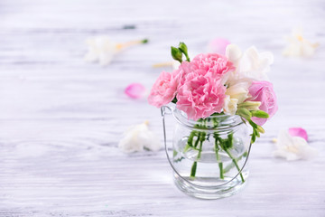 Beautiful spring flowers in glass bottle on wooden background