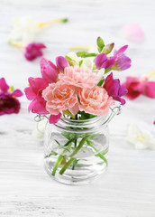 Fototapeta na wymiar Beautiful spring flowers in glass bottle on wooden background