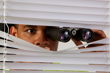 Black man peking thorough blinds