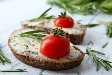 Delicious sandwiches with tomatoes and greens on table close up