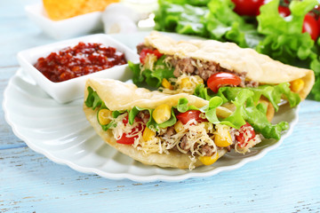Tasty taco with tomato dip on plate and vegetables on table close up