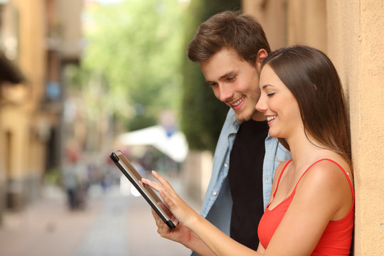 Couple browsing a tablet in the street