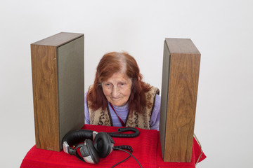 Elderly lady listening attentively to the old radio .