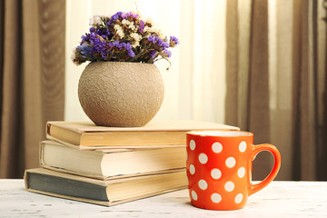 Books, cup and plant on wooden table, closeup