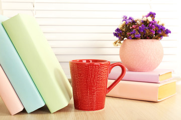 Books, cup and plant on wooden windowsill, closeup