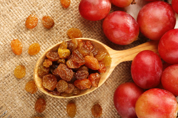 Raisins in wooden spoon with grapes on table close up