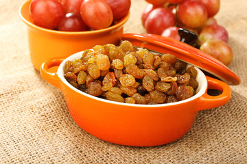 Raisins in bowl with grapes on table close up
