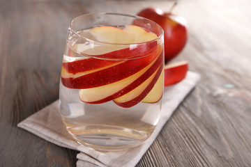 Glass of apple cider with fruits on wooden background