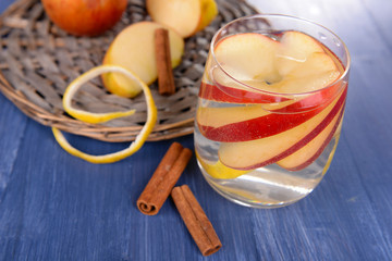Glass of apple cider with fruits and cinnamon on table close up