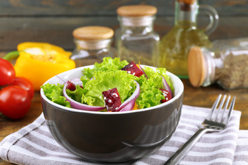 Bowl of fresh green salad on table with napkin, closeup