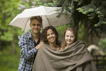 Happy woman with children, in the Park under an umbrella.