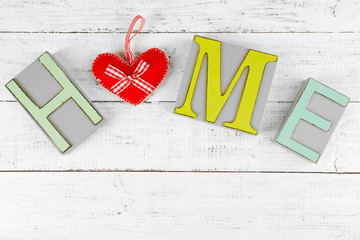 Decorative letters forming word HOME with decorative heart on wooden background
