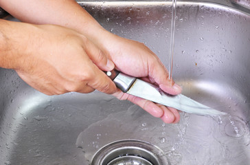 Men hands washing knife  at the sink