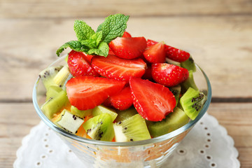 Dessert of fresh fruits in glass saucer on wooden table, closeup