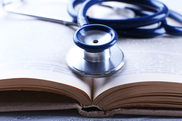 Stethoscope on book on wooden table, closeup