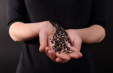 Closeup image of henna on female hand on dark background