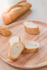 Sliced french bread with soft focus on wooden plate.