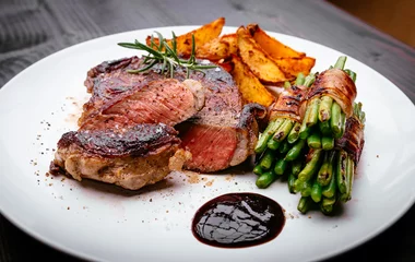 Keuken foto achterwand Steakhouse Sappige rib-eye steak met aardappelpartjes en sperziebonen