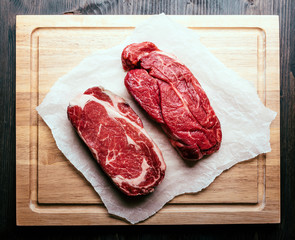 Raw steaks on chopping board - 84495047
