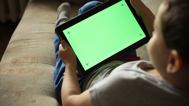 Child tilting a tablet PC with green screen
