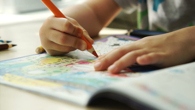 Child hands paints a colored pencils on a paper
