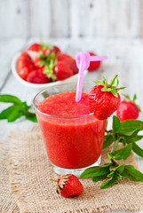 Strawberry smoothie in glass and mint leaves in rustic style